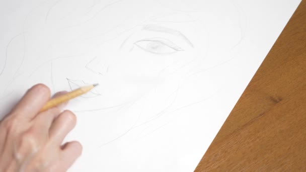 une main féminine dessine le portrait d'une fille. 4k, gros plan. Au ralenti. vue d'en haut .