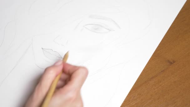 une main féminine dessine le portrait d'une fille. 4k, gros plan. Au ralenti. vue d'en haut .