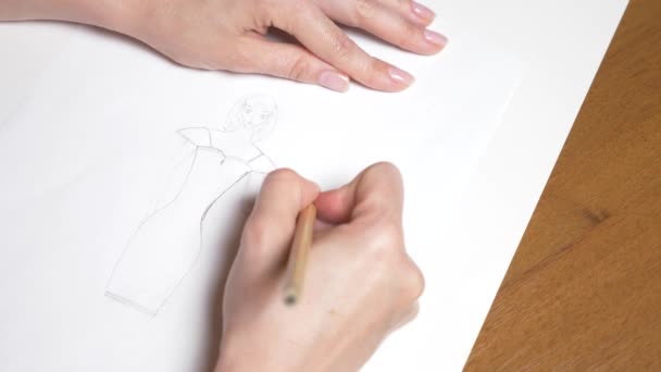 Au ralenti. 4k, gros plan, vue de dessus. une main féminine dessine avec un crayon. dessin d'une fille dans une robe . — Video