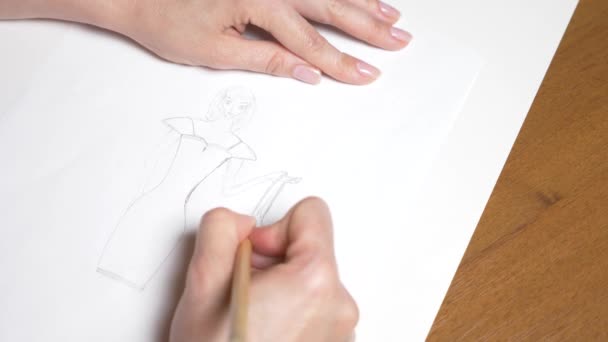 Movimento lento. 4K, close-up, vista superior. uma mão feminina desenha com um lápis. desenho de uma menina em um vestido . — Vídeo de Stock