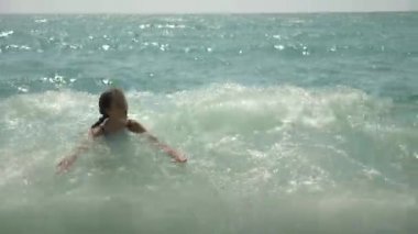 mutlu çocuk deniz dalgaları içine atlama vardır. 4k, ağır çekim.