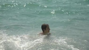 mutlu çocuk deniz dalgaları içine atlama vardır. 4k, ağır çekim.