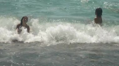 mutlu çocuk deniz dalgaları içine atlama vardır. 4k, ağır çekim.