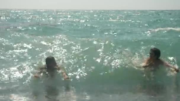 Ευτυχισμένα παιδιά είναι άλματα στο τα κύματα της θάλασσας. 4k, αργή κίνηση. — Αρχείο Βίντεο