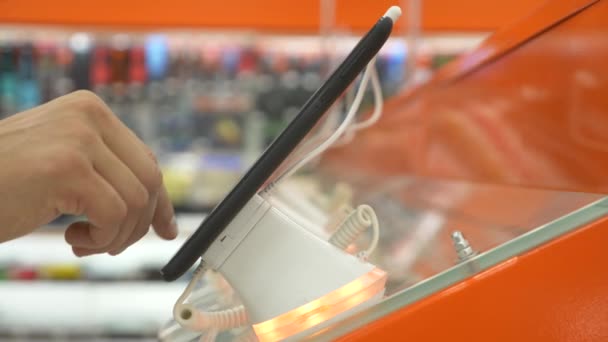 Köparen i elektronikaffär väljer en ny gadget. 4k, närbild, oskärpa bakgrund. Letar du efter en ny fred av gadget. — Stockvideo