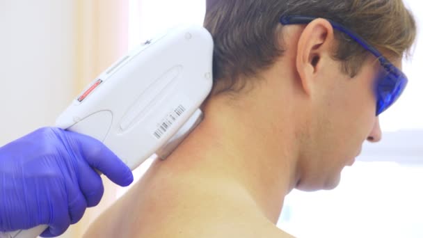 Mens laser hair removal. the doctor in blue gloves removes hair from the shoulders and neck of a handsome young man. 4k, close-up. Slow motion — Stock Video