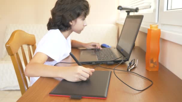 モダンな美少年ティーンエイ ジャー グラフィック タブレットに取り組んでいます 彼はノート パソコンの画面を見てください スローモーション — ストック動画