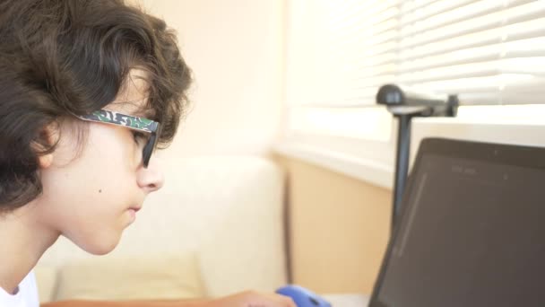 Vacker modern pojke tonåring arbetar med en ritplatta. Han ser på den bärbara skärmen. 4k, Slowmotion — Stockvideo