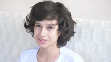 kıvırcık saçlı yakışıklı genç kamera gülüyor içine bakar ve komik bir yüz ifadesi yapar. 4 k, ağır çekim, yakın çekim