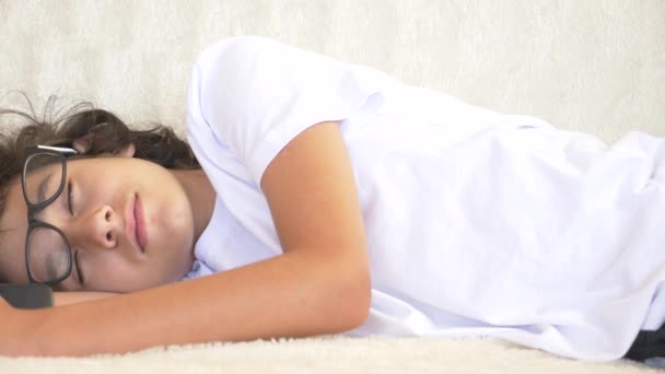 Lindo rizado adolescente durmiendo en el sofá con el teléfono en la mano. Falta de sueño. primer plano, 4k — Vídeo de stock