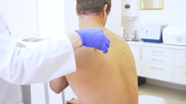 Depilación láser para hombre. el médico con guantes azules quita el pelo de los hombros y el cuello de un joven guapo. 4k, primer plano. Movimiento lento — Vídeos de Stock