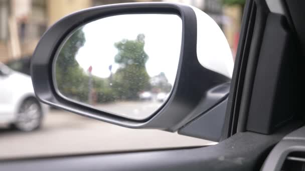 Backspegel av bilen med spår av regn. suddiga speglar i backspegeln en bil stående på vägarna, förbipasserande bilar och passerande fotgängare. 4k, Slowmotion — Stockvideo