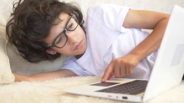 Lindo chico adolescente usando gafas duerme en el sofá al lado de la computadora portátil. 4k — Vídeo de stock