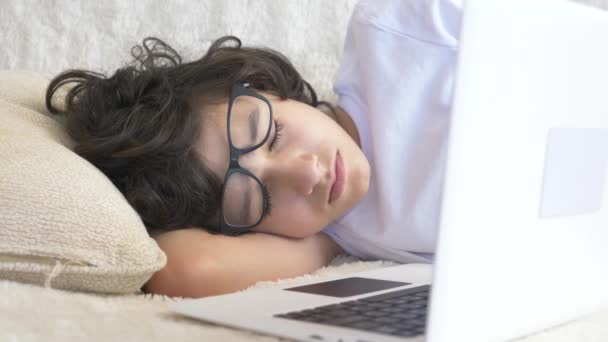 Der niedliche Teenager mit Brille schläft auf der Couch neben dem Laptop. 4k — Stockvideo