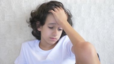 kanepede oturan üzgün yorgun genç çocuk portresi. 4k