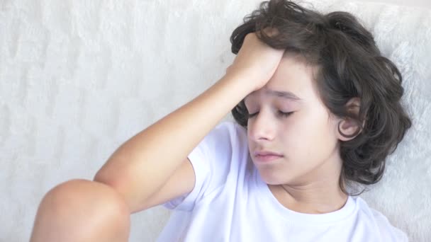 Портрет грустного уставшего подростка, который сидит на диване. 4k — стоковое видео