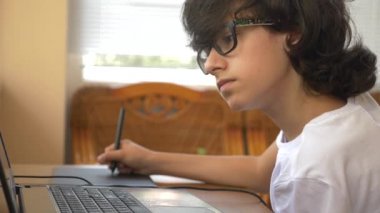 bir grafik tablet üzerinde çalışan yakışıklı modern çocuk genç. dizüstü bilgisayar ekranında görünüyor. 4k, ağır çekim