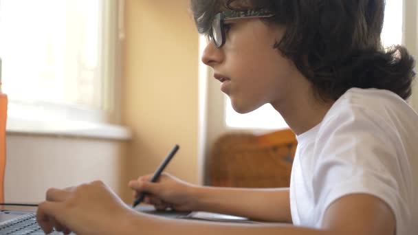 Guapo adolescente chico moderno que trabaja en una tableta gráfica. mira la pantalla del portátil. 4k, cámara lenta — Vídeos de Stock