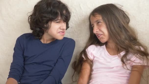 Подростки, близнецы, брат и сестра ссорятся, сидят на диване. 4к, замедленная съемка, крупный план . — стоковое видео