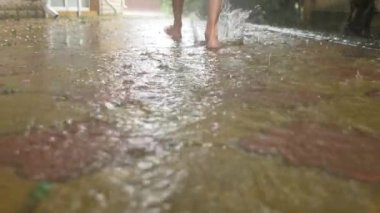 Yaz yağmuru. Çıplak ayak su birikintisi çalıştırın. Sıcak yağmur. Yağmur damlaları. 4k, ağır çekim