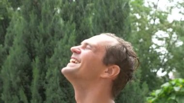 Yağmur altında genç yakışıklı bir adam. su damlaları yüzüne düşüyor. yakın çekim 4k, ağır çekim