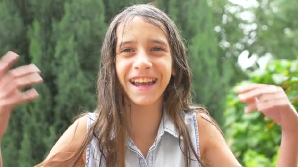 Close-up. portrait of a young girl looking at the rain in nature with wet hair. the girl rejoices in the pouring rain, drops of water fall on her face. 4k. Slow motion — Stock Video