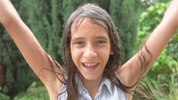 Närbild. Porträtt av en ung flicka tittar på regnet i naturen med blött hår. flickan jublar i hällande regn, droppar vatten faller på hennes ansikte. 4 k. slowmotion — Stockvideo