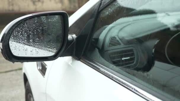 Primer plano, detalle de un coche en la lluvia en un estacionamiento exterior. 4k, cámara lenta — Vídeo de stock