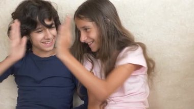 Sevimli kız ve erkek kardeşim, gülümseyerek ve yüzlerini komik ifade ile gülen çocuk portresi. Aile mutluluğu ve ilişkileri. 4k, ağır çekim