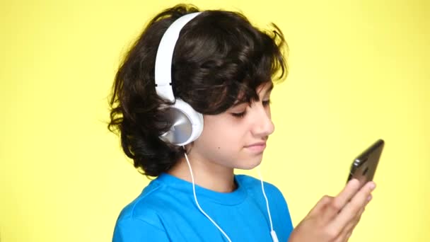 Kulaklıklar ve cep telefonu müzik renk arka plan üzerinde genç çocuk. yakın çekim, 4k, ağır çekim. — Stok video