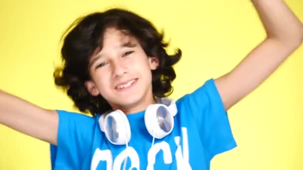 Tonåring pojke med hörlurar och mobiltelefon Lyssna på musik på färgbakgrund. närbild, 4k, slow motion. — Stockvideo
