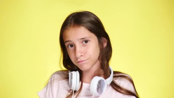 Девочка-подросток с наушниками и мобильным телефоном слушает музыку на цветном фоне. крупный план, 4k, замедленная съемка . — стоковое видео