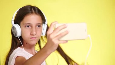 Genç kız mobil müzik renk arka plan üzerinde telefon ve kulaklık ile. yakın çekim, 4k, ağır çekim. selfi smartphone yapar