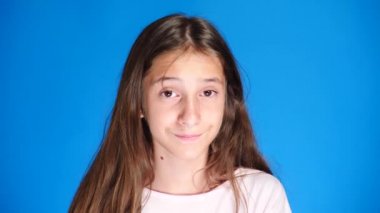 şirin kız Genç kamera gülüyor içine bakar ve komik bir yüz ifadesi yapar. 4 k, ağır çekim, yakın çekim. renk arka plan
