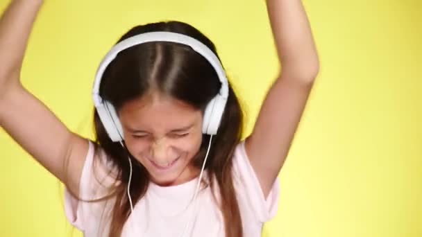 色の背景に音楽を聴く携帯電話とヘッドフォンの 10 代の少女。クローズ アップ、4 k、スローモーション. — ストック動画