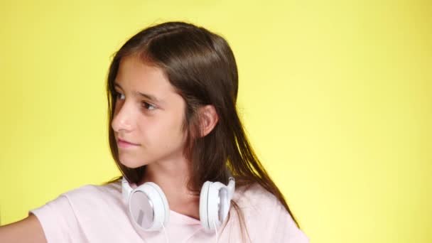 Εφηβικό κορίτσι με ακουστικά και το κινητό τηλέφωνο, ακούτε μουσική στο χρώμα φόντου. γκρο πλαν, 4k, αργή κίνηση. κάνει selfi σε smartphone — Αρχείο Βίντεο