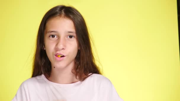 La fille mâche du chewing-gum sur un fond coloré et rit. 4k, gros plan, prise de vue au ralenti . — Video