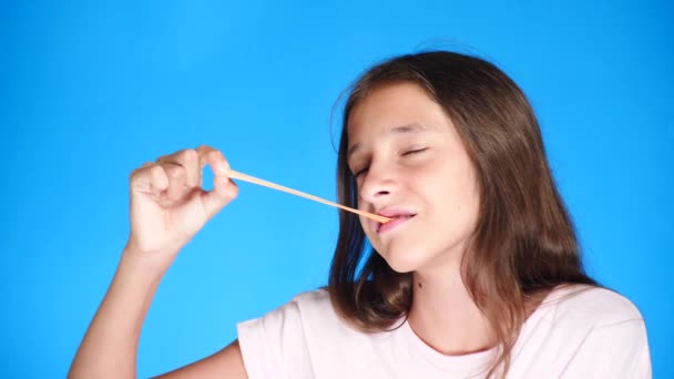 Meisje die zich uitstrekt van kauwgom op een gekleurde achtergrond. 4 k, close-up, slow-motion-video schieten. — Stockvideo