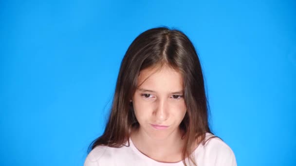 Nahaufnahme. gut aussehende schmollende Mädchen schmollt Lippen, auf blauem Hintergrund. beleidigtes Teenie-Mädchen — Stockvideo