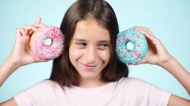 Portre. having oyunculuk ile renkli donut yüzüne karşı uzun tüyleri, komik bir kızla portresi. İfadeler, diyet kavramı, arka plan rengi
