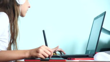 yakın çekim. Bir kız beyaz kulaklık grafik tablet üzerinde çizer. Serbest. El ile bir kırmızı siyah tablet üzerinde hareketli bir pikap iğnesi. 4k, ağır çekim. renk arka plan. kopya alanı