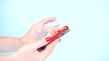 yakın çekim, eller kırmızı manikür ile renkli bir arka plan üzerine bir akıllı telefon kullanın. 4k, ağır çekim çekim