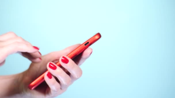 Крупним планом, жіночі руки з червоним манікюром використовують смартфон на кольоровому фоні. 4k, повільна стрільба — стокове відео