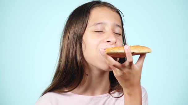 Pizza. Rapaz feliz adolescente segurando pizza. O conceito de nutrição. A rapariga está a comer pizza. Homem encaracolado sorridente com uma deliciosa pizza. Pizzaria de publicidade. num fundo azul. 4k câmera lenta — Vídeo de Stock