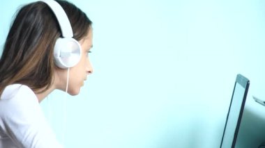yakın çekim arka plan. Renkli bir arka planda beyaz kulaklık güzel bir genç kızı dizüstü bilgisayar ekranında görünüyor. ağır çekim, 4k.