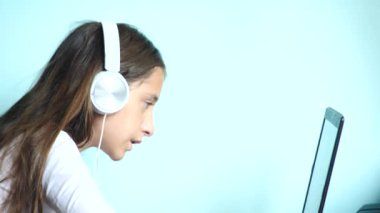 yakın çekim arka plan. Renkli bir arka planda beyaz kulaklık güzel bir genç kızı dizüstü bilgisayar ekranında görünüyor. ağır çekim, 4k