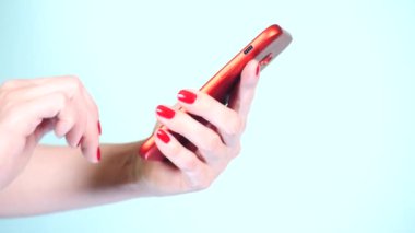 yakın çekim, eller kırmızı manikür ile renkli bir arka plan üzerine bir akıllı telefon kullanın. 4k, ağır çekim çekim