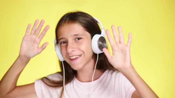 色の背景に音楽を聴くヘッドフォン十代の少女。クローズ アップ、4 k、スローモーション. — ストック動画