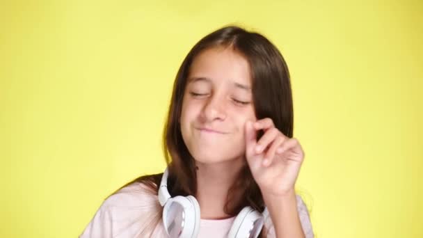 Дівчинка-підліток з навушниками, що слухають музику на кольоровому фоні. крупним планом, 4k, повільний рух . — стокове відео