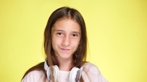 十几岁的女孩戴着耳机和手机, 在彩色背景下听音乐。特写, 4k, 慢动作。显示手势, ok, 超级 — 图库视频影像